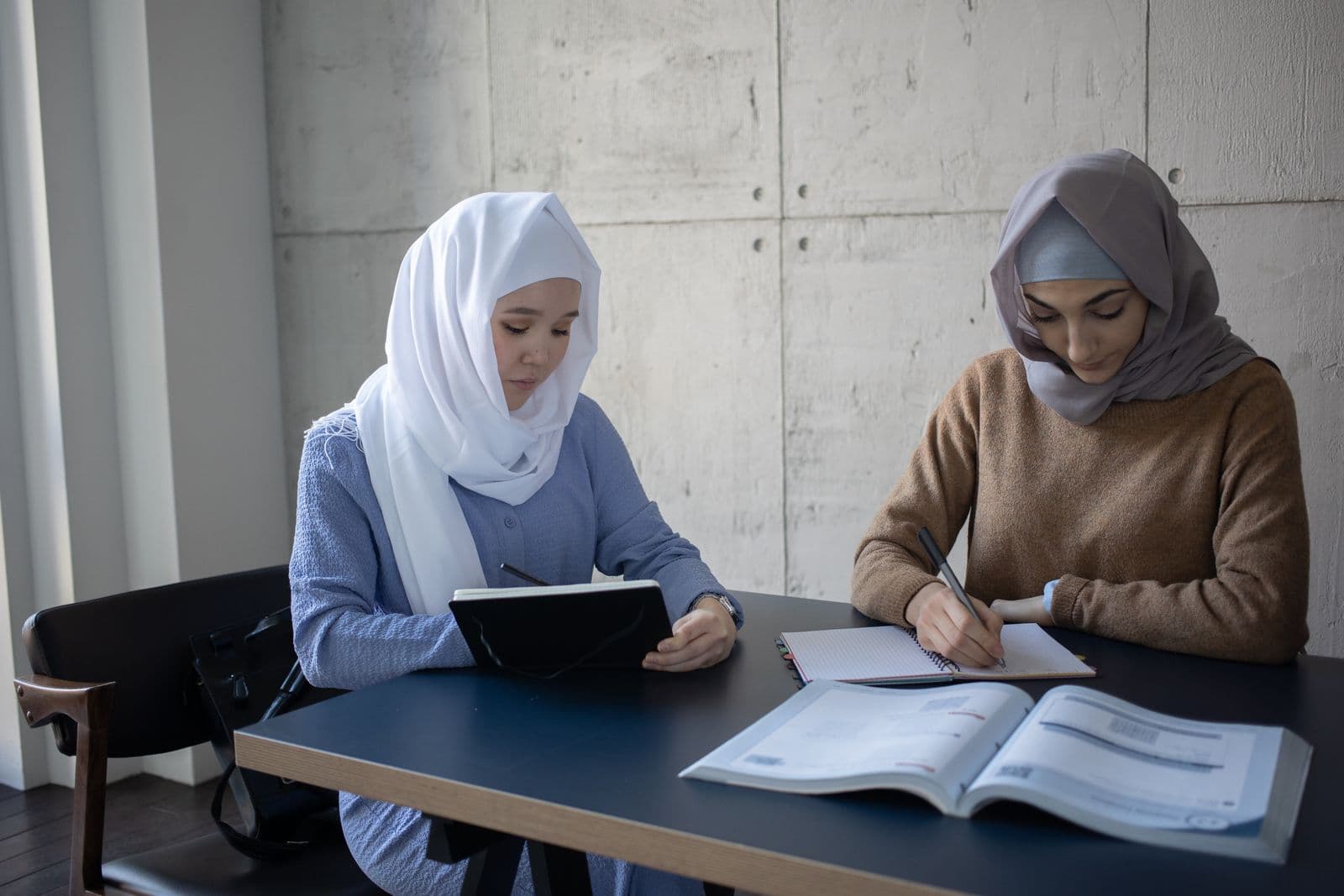 Two learners studying together with textbooks at British Training Institute in Sharjah